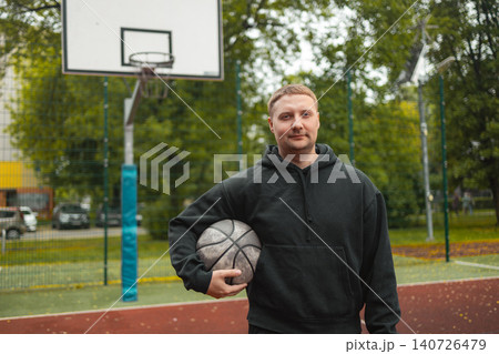Portrait of smiling man holding basketball ball on court 140726479