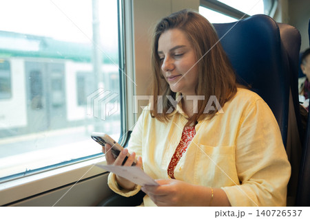 Young woman using smartphone while traveling by train 140726537