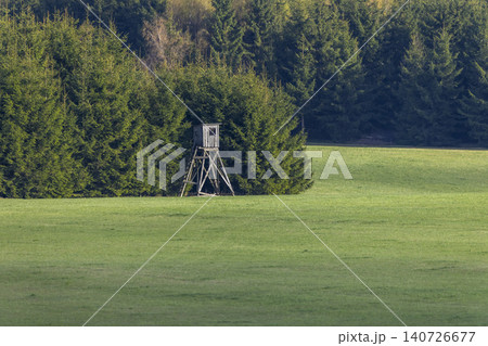 Wooden hunting stand in a green field bordering forest in Czechia 140726677