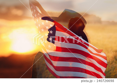 Woman in cowboy hat silhouette with the American Flag inside her head. 4th July celebration concept. Double exposure Woman in cowboy hat silhouette with the American Flag inside her head. 4th July celebration concept. Double exposure 140726698