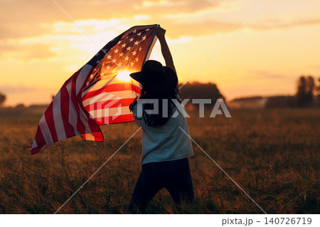 Patriotic Independence day 4th of July Woman farmer in the agricultural field with american flag on sunset. Patriotic Independence day 4th of July Woman farmer in the agricultural field with american flag on sunset. 140726719