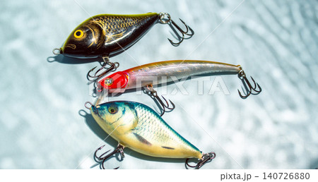 Colorful fishing lures and tackles on blue background with shadow from water, ready for fishing Colorful fishing lures and tackles on blue background with shadow from water, ready for fishing 140726880