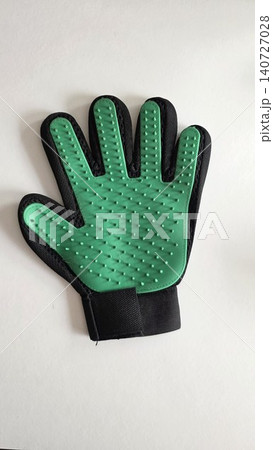 Green and black silicone pet grooming deshedding glove lying flat against plain white background, concept of domestic animal care and hygiene Green and black silicone pet grooming deshedding glove lying flat against plain white background, concept of domestic animal care and hygiene 140727028