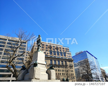 Washington, D.C., USA - March 3, 2025: A granite monument with a memorial to Rear Admiral David Farragut. Tall trees and modern buildings line both sides of the monument. Washington, D.C., USA - March 3, 2025: A granite monument with a memorial to Rear Admiral David Farragut. Tall trees and modern buildings line both sides of the monument. 140727107