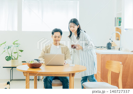リビングでパソコンを見る若い夫婦 リビングでパソコンを見る若い夫婦 140727337