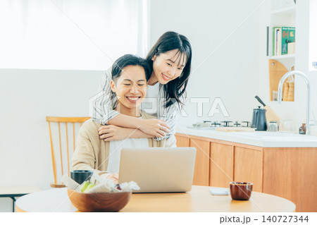 リビングでパソコンを見る若い夫婦 リビングでパソコンを見る若い夫婦 140727344