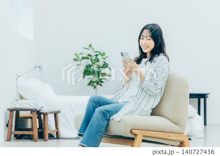リビングでスマホを見る若い女性 140727436