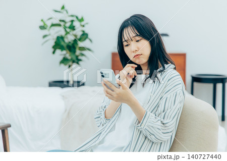 リビングでスマホを使って悩む若い女性 リビングでスマホを使って悩む若い女性 140727440