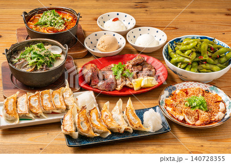 居酒屋のテーブルに並ぶ多彩な一品料理と餃子、鍋の宴会メニュー盛り合わせ 居酒屋のテーブルに並ぶ多彩な一品料理と餃子、鍋の宴会メニュー盛り合わせ 140728355