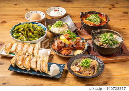 居酒屋のテーブルに並ぶ多彩な一品料理と餃子、鍋の宴会メニュー盛り合わせ 居酒屋のテーブルに並ぶ多彩な一品料理と餃子、鍋の宴会メニュー盛り合わせ 140728357