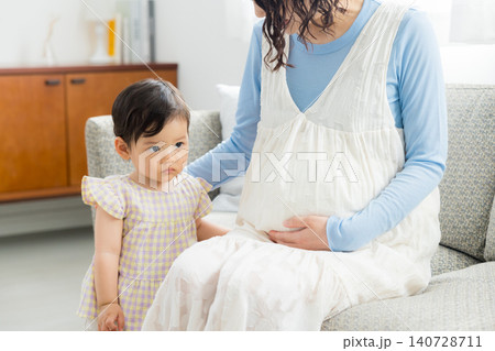 1歳の女の子を抱っこする妊婦のお母さん 1歳の女の子を抱っこする妊婦のお母さん 140728711