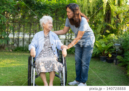 Caregiver help Asian elderly woman disability patient sitting on wheelchair in park. Caregiver help Asian elderly woman disability patient sitting on wheelchair in park. 140728888