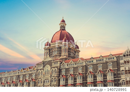 Mumbai Maharashtra India Jan 18 2026 Architectural detail of the iconic red central dome and Victorian Gothic facade of the Taj Mahal Palace Hotel during a vibrant sunset with a colorful orange and pu Mumbai Maharashtra India Jan 18 2026 Architectural detail of the iconic red central dome and Victorian Gothic facade of the Taj Mahal Palace Hotel during a vibrant sunset with a colorful orange and pu 140728991