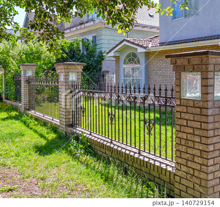 Ornate Brick Fence with Wrought Iron in Sunny Residential Yard Ornate Brick Fence with Wrought Iron in Sunny Residential Yard 140729154