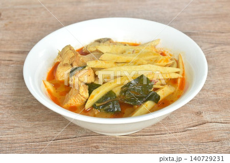 spicy boiled slice fresh bamboo shoot with pork in coconut milk Thai red curry soup on bowl 140729231