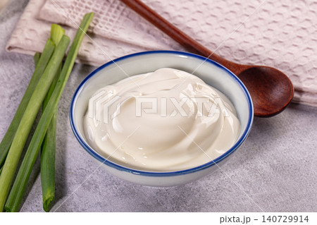Sour cream in bowl with fresh green onions on gray table Sour cream in bowl with fresh green onions on gray table 140729914