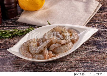 Fresh raw shrimp in white bowl with lemon and herbs on wooden table 140729942