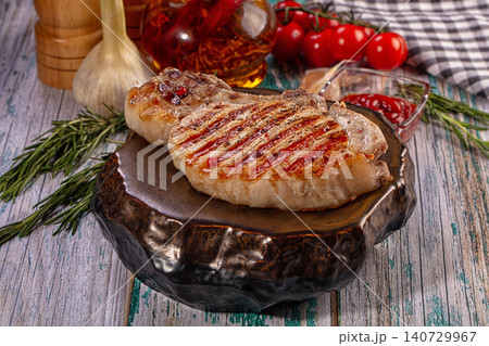 Grilled pork chop with rosemary, garlic and tomatoes on rustic wooden table Grilled pork chop with rosemary, garlic and tomatoes on rustic wooden table 140729967