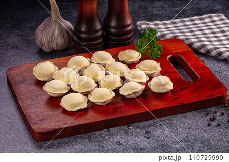 Uncooked Pelmeni Dumplings on Wooden Board with Garlic and Spices 140729990