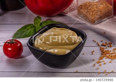Smooth mustard in black bowl with tomato and basil Smooth mustard in black bowl with tomato and basil 140729998