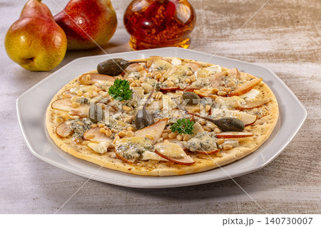 Pear and blue cheese flatbread pizza with pine nuts and capers on white plate Pear and blue cheese flatbread pizza with pine nuts and capers on white plate 140730007