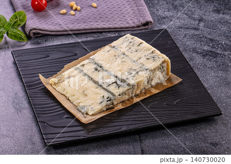 Gorgonzola cheese block on black plate, accompanied by fresh basil, pine nuts, and cherry tomatoes Gorgonzola cheese block on black plate, accompanied by fresh basil, pine nuts, and cherry tomatoes 140730020