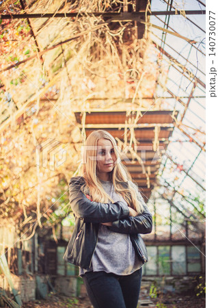 Confident blonde woman with crossed arms in overgrown autumn greenhouse Confident blonde woman with crossed arms in overgrown autumn greenhouse 140730077