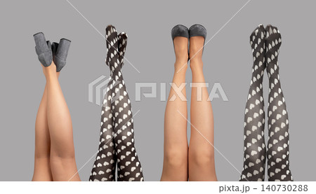 Female legs raised upward wearing heels and patterned tights isolated white background. Woman limbs lifted vertically in playful hosiery and shoes against clean backdrop. Concept of fashion Female legs raised upward wearing heels and patterned tights isolated white background. Woman limbs lifted vertically in playful hosiery and shoes against clean backdrop. Concept of fashion 140730288