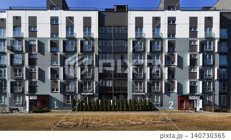 Modern residential buildings forming symmetrical urban composition with clean facade lines. Apartment structures show geometric design and contemporary style Modern residential buildings forming symmetrical urban composition with clean facade lines. Apartment structures show geometric design and contemporary style 140730365