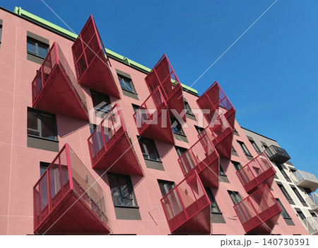 Pink modern building with unusual rectangular balconies in pop art style design. Residential structure shows bold geometry and vibrant facade composition. Concept of contemporary Pink modern building with unusual rectangular balconies in pop art style design. Residential structure shows bold geometry and vibrant facade composition. Concept of contemporary 140730391