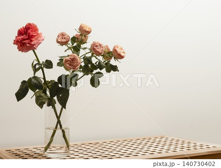 Small bouquet of roses in vase on wooden table with warm tone background. Floral arrangement placed in cozy interior composition with natural mood. Concept of decorative home styling.. 140730402