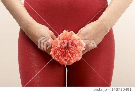 Woman holding red carnation near body representing menstruation concept. Floral symbol used for feminine health awareness and reproductive system theme. Concept of gynecology education.. Woman holding red carnation near body representing menstruation concept. Floral symbol used for feminine health awareness and reproductive system theme. Concept of gynecology education.. 140730491