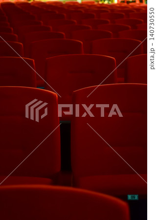 Close up of red theatre chair. Empty red seats in the theatre. Patterns of chairs in a theater. Seats background pattern photo. Close up of red theatre chair. Empty red seats in the theatre. Patterns of chairs in a theater. Seats background pattern photo. 140730550