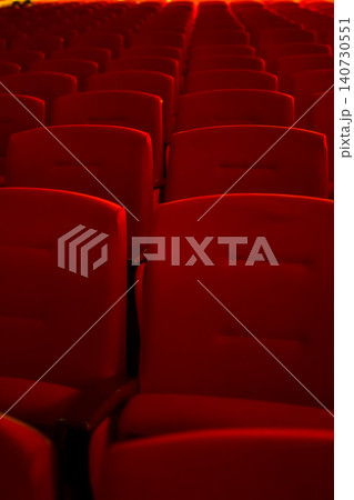 Close up of red theatre chair. Empty red seats in the theatre. Patterns of chairs in a theater. Seats background pattern photo. Close up of red theatre chair. Empty red seats in the theatre. Patterns of chairs in a theater. Seats background pattern photo. 140730551