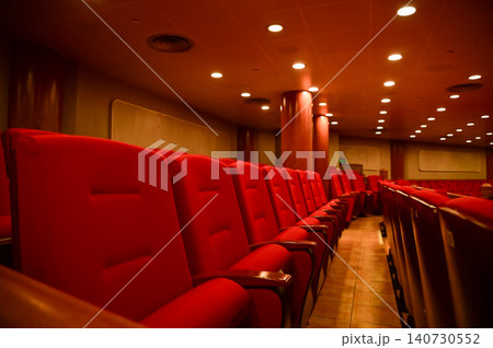Close up of red theatre chair. Empty red seats in the theatre. Patterns of chairs in a theater. Seats background pattern photo. Close up of red theatre chair. Empty red seats in the theatre. Patterns of chairs in a theater. Seats background pattern photo. 140730552