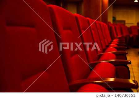 Close up of red theatre chair. Empty red seats in the theatre. Patterns of chairs in a theater. Seats background pattern photo. Close up of red theatre chair. Empty red seats in the theatre. Patterns of chairs in a theater. Seats background pattern photo. 140730553