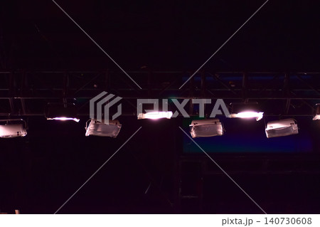 Set of professional stage lighting equipment on the stage for gig illumination of theater or concert hall. Stage lights, spotlights and laser beams. Rays of light from the floodlights. Concert light. 140730608