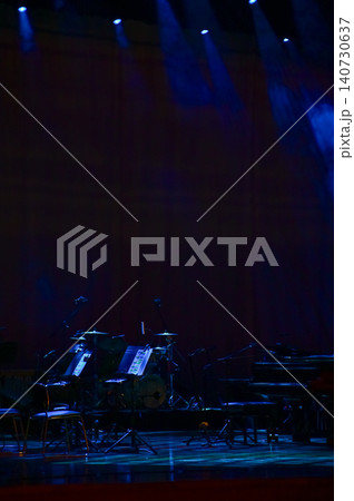 A set of musical instruments on an empty stage of the theater, lit by spotlights, before the performance. Stage before concert. A set of musical instruments on an empty stage of the theater, lit by spotlights, before the performance. Stage before concert. 140730637