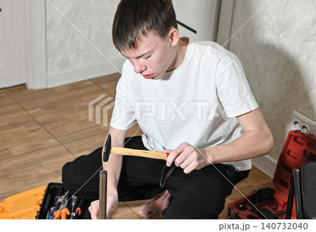 Young person working on stool assembly with tools in a home setting Young person working on stool assembly with tools in a home setting 140732040