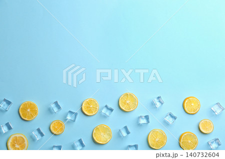 Lemonade layout with juicy lemon slices and ice cubes on light blue background, top view. Space for text 140732604