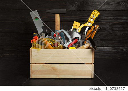 Wooden crate with different carpenter's tools on black table Wooden crate with different carpenter's tools on black table 140732627