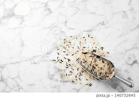 Mix of brown and polished rice with scoop on marble table, top view. Space for text 140732645
