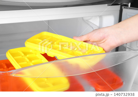 Woman taking tray with ice cubes from fridge, closeup Woman taking tray with ice cubes from fridge, closeup 140732938