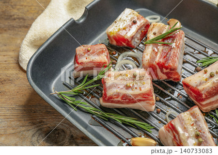 Grill pan with raw ribs and seasonings on wooden table, closeup Grill pan with raw ribs and seasonings on wooden table, closeup 140733083