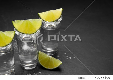 Mexican Tequila shots, lime slices and salt on black table. Space for text 140733109