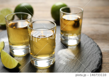 Mexican Tequila shots, lime slices and salt on wooden table Mexican Tequila shots, lime slices and salt on wooden table 140733110