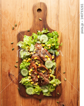 Juicy fried pork tenderloin steaks with sweet corn, green lettuce cucumbers salad and pumpkin seeds Juicy fried pork tenderloin steaks with sweet corn, green lettuce cucumbers salad and pumpkin seeds 140733281