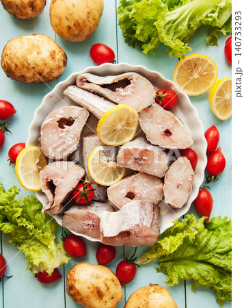 Fresh pollock seafood steaks with lettuce and cherry tomatoes seasoned with salt and lemon in pan. Fresh pollock seafood steaks with lettuce and cherry tomatoes seasoned with salt and lemon in pan. 140733293