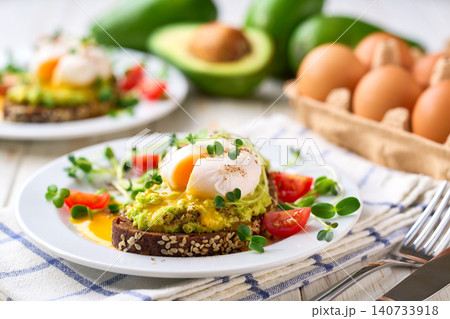 Avocado sandwiches with poached egg and cereal bread in a white wooden table. Avocado sandwiches with poached egg and cereal bread in a white wooden table. 140733918