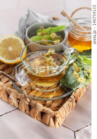 Herbal tea with linden flowers, honey, and lemon on a wicker tray Herbal tea with linden flowers, honey, and lemon on a wicker tray 140734115